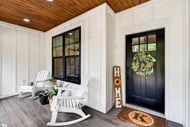 An oversized covered front porch with stained wood ceilings sets - photo 5